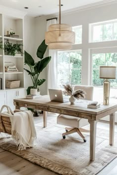 a desk with a laptop on top of it in front of a large window and bookshelf