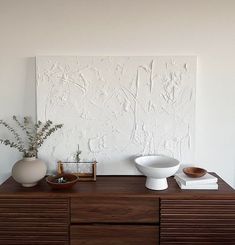 two white vases sitting on top of a wooden dresser