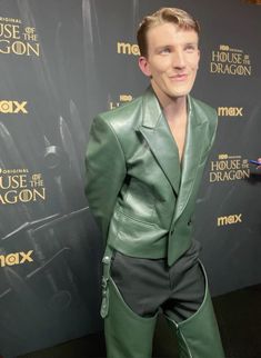 a man in a green suit posing for a photo on the red carpet at house of the dragon