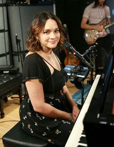 a woman sitting at a piano in front of a microphone