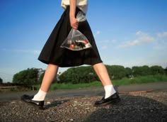 a woman walking down the street carrying a clear bag with fish in it's pouch