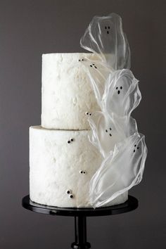 a three tiered cake with white frosting and ghost decorations