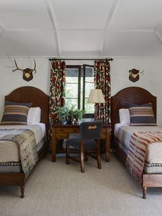 two twin beds in a bedroom with antlers on the wall and curtains over them