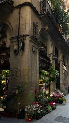 an old building with lots of flowers on the sidewalk