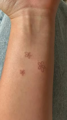 a person with a small tattoo on their arm that has three flowers in the middle