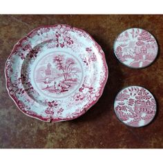 three pink and white plates sitting next to each other on top of a brown table