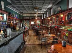 an old fashioned bar with lots of tables and chairs in the middle of it's long hallway