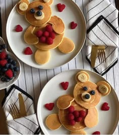 two white plates topped with pancakes covered in fruit and teddy bear shaped toppings,