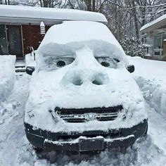 a car that is covered in snow with its hood up and eyes wide open to the side