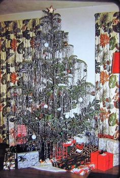 a christmas tree in the corner of a room with curtains and presents on the floor