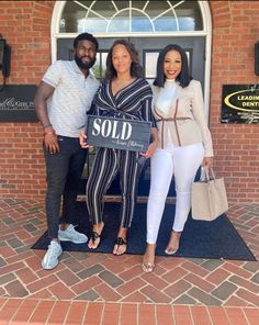 two people standing in front of a door holding a sold sign