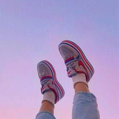 a person with their feet up in the air, wearing sneakers and blue denims