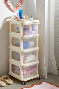 a white cart with four baskets on top of it in front of a pink rug