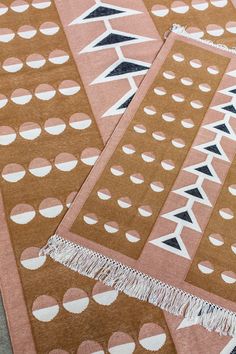 two brown and white rugs on the ground with circles, dots and fringes