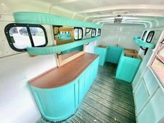 an interior view of a bus with blue cabinets and counter tops, along with wood flooring