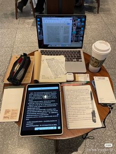 an open laptop computer sitting on top of a wooden table next to a cup of coffee