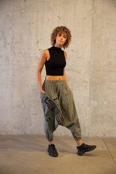 a woman standing in front of a concrete wall with her hands on her hips and looking at the camera