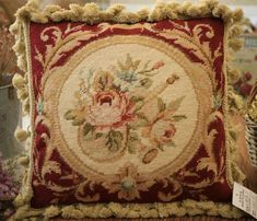 a decorative pillow on display in a store with flowers and leaves embroidered on the back