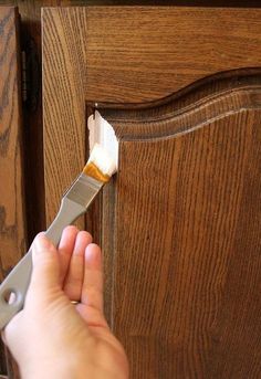 someone using a paint brush to apply wood grain on a cabinet door with an adhesive tape