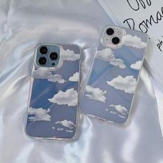 two iphone cases sitting next to each other on top of a white cloth covered surface