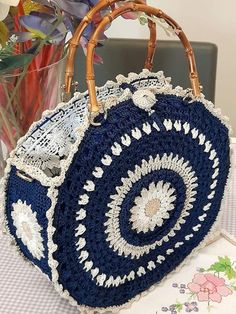 a blue and white purse sitting on top of a table next to a vase filled with flowers