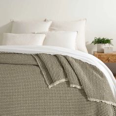 a bed with white pillows and blankets on top of it next to a wooden table