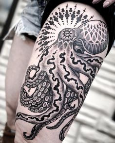 an octopus tattoo on the leg of a woman's thigh, with black and white ink