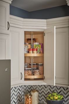 a kitchen with white cabinets and black and white checkered backsplash, an open spice rack in the corner