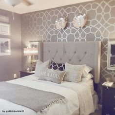 a bedroom with a bed, nightstands and two mirrors on the wall above it