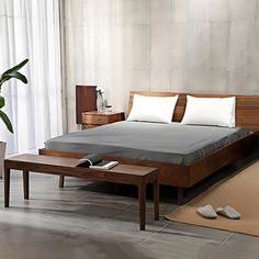 a bedroom with a bed, nightstands and plants in the corner on the floor