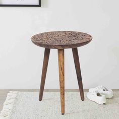 a small wooden table sitting on top of a rug next to a pair of white shoes