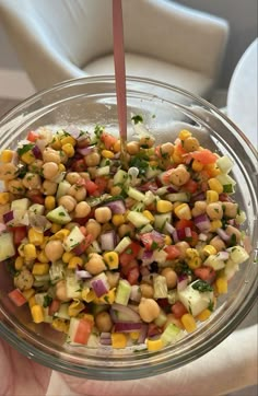 a person holding a glass bowl filled with vegetables and garnishes on top of it