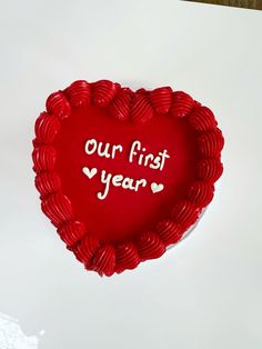 a red heart shaped cake with the words our first year written in white on it