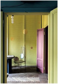 a room with yellow walls and two chairs in front of a pink door that leads to another room