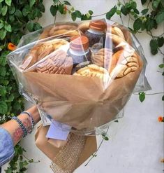 a person holding a bouquet of bread wrapped in plastic