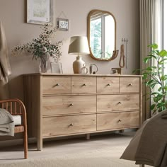 a bedroom scene with focus on the dresser and bed sideboard, mirror and plants