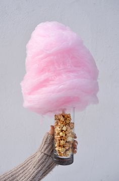 a person is holding a pink cotton candy in a glass jar filled with granola