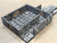 a model of a castle made out of stone blocks on a wooden table with one door open