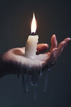 a person holding a lit candle in their hand with water dripping from the top and bottom