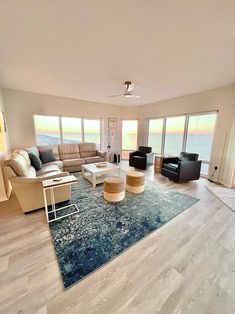 a living room filled with furniture and large windows overlooking the ocean on a sunny day