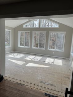 an empty room with three windows and no one on the floor in front of it