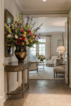 a vase filled with lots of flowers sitting on top of a wooden table next to a doorway