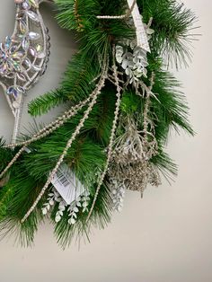 a christmas wreath with ornaments hanging from it's sides on a wall next to a clock