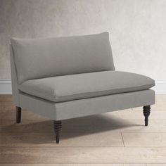 a gray couch sitting on top of a hard wood floor next to a white wall