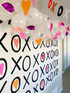 balloons are hanging from the ceiling in front of a wall with letters and numbers on it