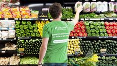 a man standing in front of a display of fruits and vegetables at a grocery store