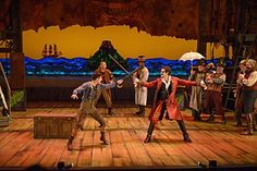 a group of people standing on top of a wooden floor in front of a stage