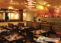 an empty restaurant with tables and chairs in front of the counter, along with lights hanging from the ceiling