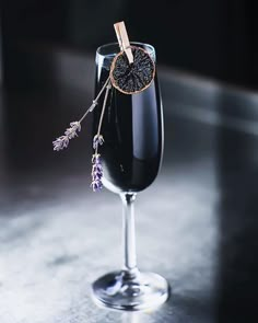 a wine glass filled with black liquid and lavender sprigs