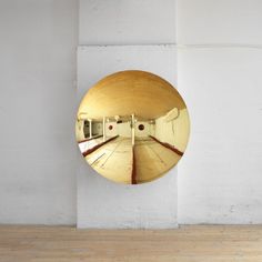 a round mirror mounted to the side of a white wall next to a wooden floor